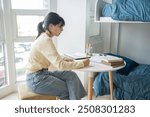 Student asian woman reading book in dorm room college student do homework in university dormitory.