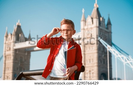 Student with backpack and books. Happy confident pupil ready for education in England. Portrait of boy with Tower bridge on background. Kid in glasses. English language courses.