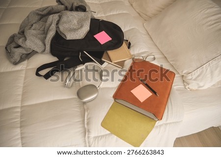 Student backpack, headphones, and study materials lying on a white bed