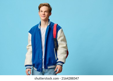 student with a backpack on his shoulder posing on a blue background - Shutterstock ID 2164288347