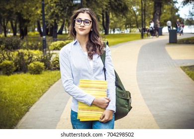 The student. Beautiful Indian girl with books in the park. Attractive young woman with books and a backpack. Spanish female - Shutterstock ID 704298502