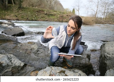 Student in biology taking sample of natural water