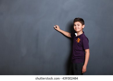 student boy  beside a big blackboard for drawing, writing and show the place for your text, - Powered by Shutterstock