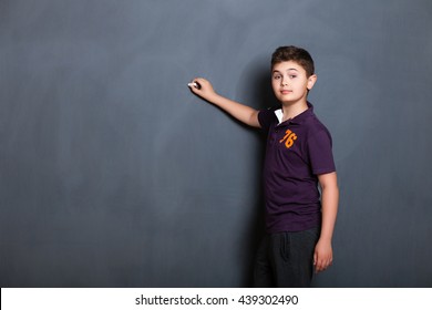 student boy  beside a big blackboard for drawing, writing and show the place for your text, - Powered by Shutterstock