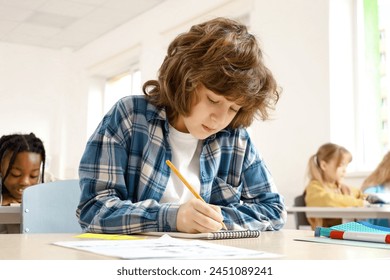 Student boy doing test in primary school. Children writing notes in classroom on the background. Education concept. Back to school - Powered by Shutterstock