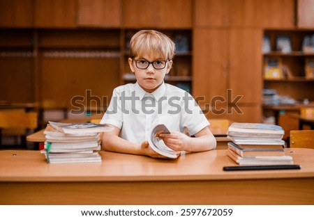 Student boy reading a book and looking very surprised in the school classroom.