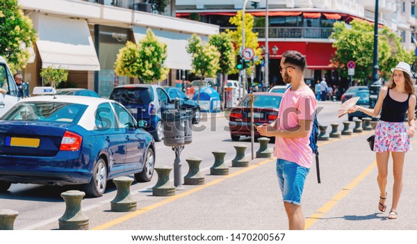 Student\
calling a taxi while wearing a backpack on his shoulder and\
standing on a city boardwalk, e hailing\
concept