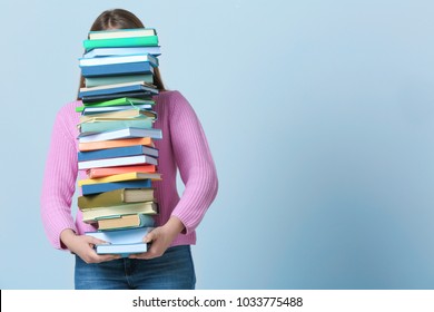 Student Carrying Stack Of Textbooks On Color Background. Studying Process