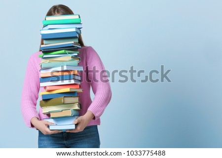 Student carrying stack of textbooks on color background. Studying process