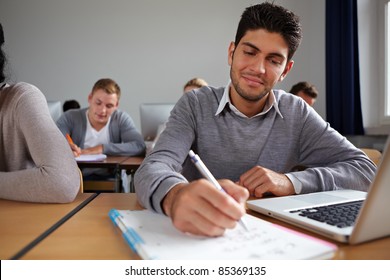 Student with computer taking notes in university class