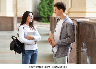 Student couple having break after classes, talking and flirting in college campus