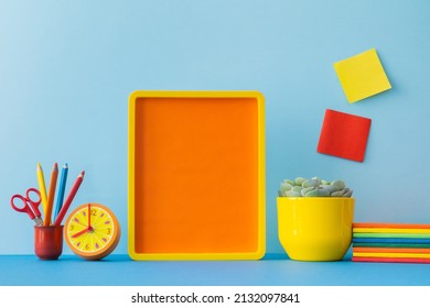 Student Creative Desk With Picture Frame Mock Up Colorful School Supplies, Notes, Notebooks And Blue Wall Background. Back To School.