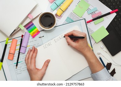 Student Desk. The Girl Makes Notes On Stickers In The Study Schedule. The Process Of Homeschooling Or Preparing Homework . Top View Of The Table With Student Stationery And Notes.