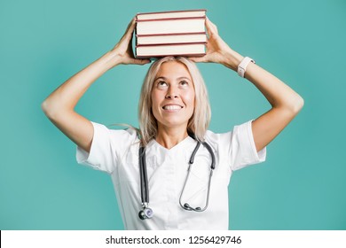 Student doctor standing on a green background holding a stack of books on his head