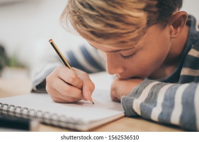 Student Drawing With Pencil On The Notebook. Boy Doing Homework Writing On A Paper. Kid Hold A Pencil And Draw A Manga At Home. Teen Drawing Sitting At The Table. Education Art Talent Ability Concept.