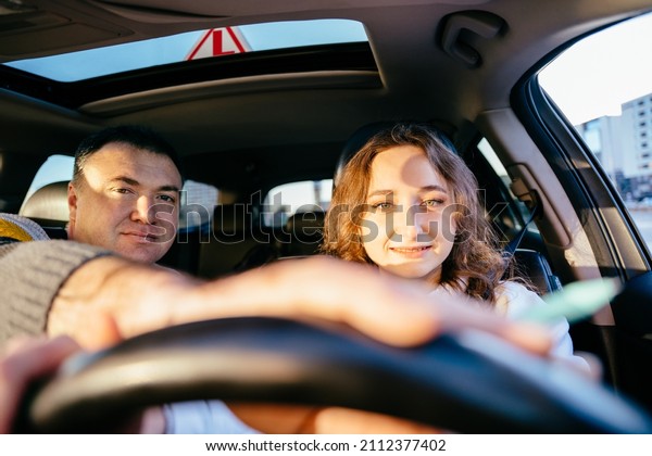 A student driver with her driving instructor.\
Driving school or test. Beautiful young woman learning how to drive\
car together with her\
instructor.