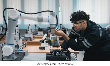 Student engineer Assembling Robotic Arm with computer in Technology Workshop. Service Engineer Holding Robot Controller and Checking Robotic Arm Welding Hardware.