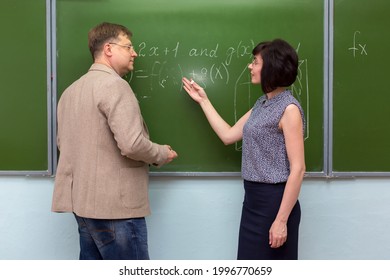 A student explains to the teacher the solution of the problem at the blackboard.
