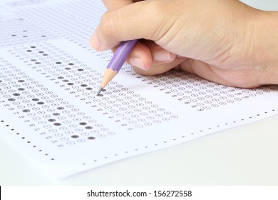 Student filling out answers to purple answer sheet with purple pencil  - Shutterstock ID 156272558