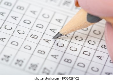 The student fills in the answers to the test in the exercise and examination paper with a pencil. computer worksheet with pencil in school test room, education concept.