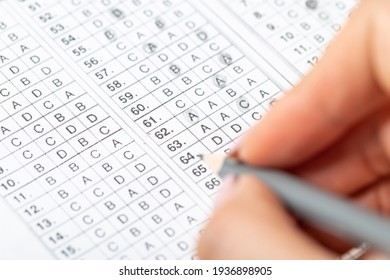 The student fills in the answers to the test in the exercise and examination paper with a pencil. computer worksheet with pencil in school test room, education concept.
