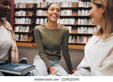 Student, friends and book discussion in library with smile for education, learning or knowledge at university. Group of happy women enjoy conversation, book club or social study for research project