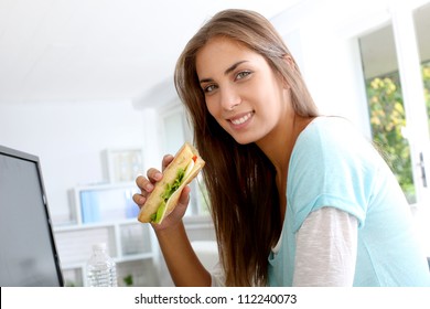 Student Girl Eating Sandwich In Front Of Desktop