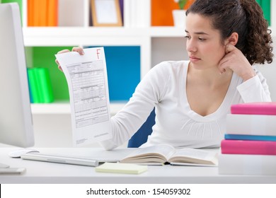 student girl holding a test paper with a failing grade