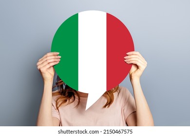 Student Girl Holds Blank White Speech Bubble With Italian Flag Isolated Over Grey Studio Background. Woman Holding A Round Information Piece Of Paper Dialog