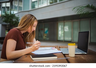 Student Girl Reviewing Her Notes For The Exam. She Seems Focus And She Is At The Uni Campus.