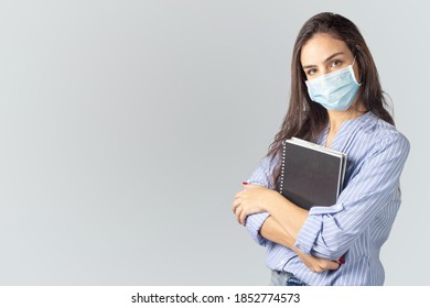 Student Girl With A School Notebook In Her Hands And A Facial Protect Face Mask In Her Face.