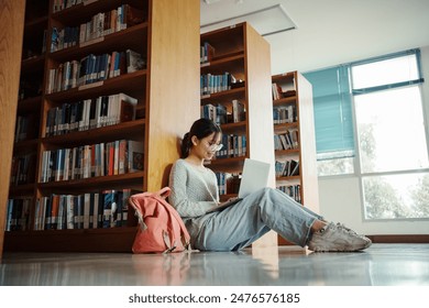 Student girl sitting on floor and using laptop, Writes notes for paper, Essay, Study for class assignment. Diverse group of Students Learning, Studying for Exams. - Powered by Shutterstock