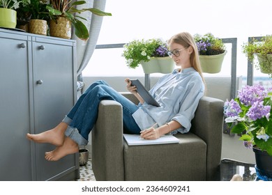 Student girl studying at home, sitting at home in an armchair, using digital tablet - Shutterstock ID 2364609241