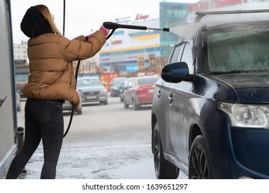 The Student Girl In Warm Clothes Clearing Dirty Car In Outdoor Manual Washing In Winter Cold Time. Wet Works.