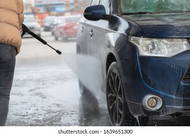 The Student Girl In Warm Clothes Clearing Dirty Car In Outdoor Manual Washing In Winter Cold Time. Wet Works.