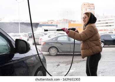 The Student Girl In Warm Clothes Clearing Dirty Car In Outdoor Manual Washing In Winter Cold Time. Wet Works.