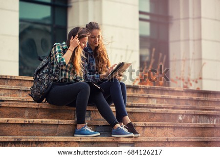 Student girls having a chat in front of university after class. Back to school concept.