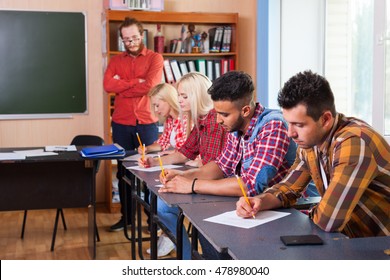 Student Group Write Test, Professor Observing, Young Diverse People Sit Desk University Classroom Examination High Shool Education