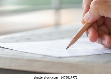 Student Hand Testing Doing Test Exam With Pencil Drawing Selected Choices On Answer Sheet In School Final Exams At College Or University. Taking Multiple Choice For Assessment In Examination Classroom