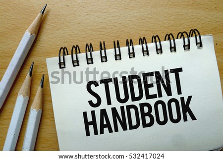 Student Handbook text written on a notebook with pencils