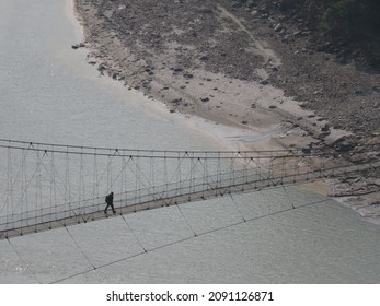 Student Headed Home From School Walking Over A Suspension Bridge In Nepal