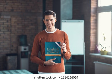 Student Holding Book. Handsome Postgraduate Smart Student Smiling While Holding English Grammar Book