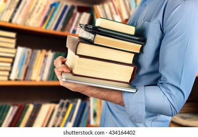 Student Holding Books And Laptop In Library