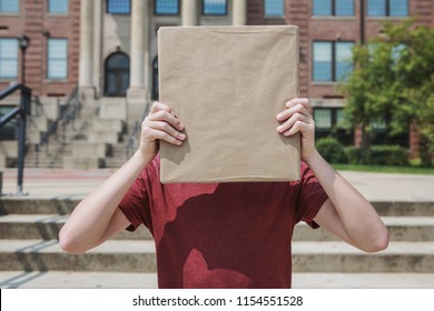 Student Holding Kraft Paper Covered Text Book In Front Of Face At School, Hidden Identity