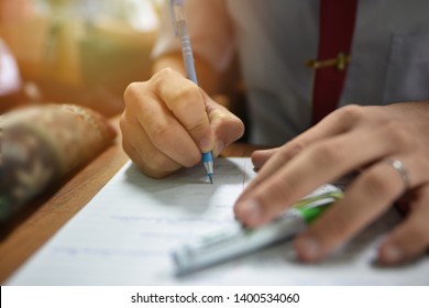 Student holding a pen taking lecture note or doing writing assignment in the classroom; closed up photo of young learner using a pen during the written test in collage or university training center - Shutterstock ID 1400534060