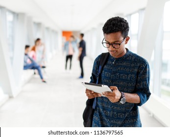 A Student From India Stands With A Tablet At The University. Students In The Background. The Photo Illustrates Education, College, School, Or University.