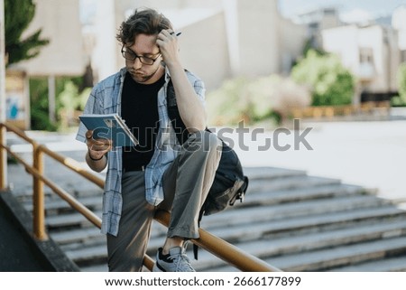 A student intensely studies their notes while sitting outdoors on a railing in a school yard. Engaged and focused, they embody the spirit of education and perseverance in an academic environment.