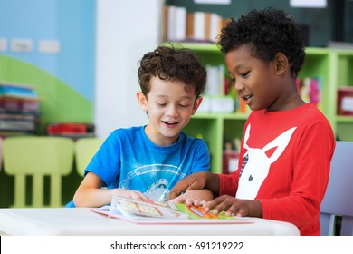 Student in international preschool reading a magazine book together in school library, education, kid and study concept