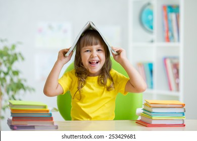 Student kid girl with a book over her head at nursery - Shutterstock ID 253429681