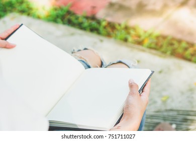 Student Learning Study Read Book Concept. Close-up Female Hand Holding Book And Reading In The University Campus. The Book Is Open On Blank Pages. Selective Focus On Right Hand.